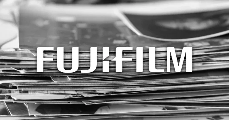 Rolls of black-and-white film beside contact prints on a darkroom workbench, illustrating the May 2026 panic over a Fujifilm announcement